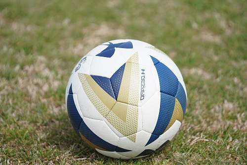 team white and blue Under Armour soccer ball on green field ball